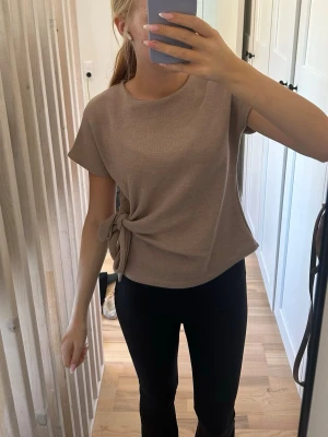 Beige topp med knyt från Zara - Säljer en beige topp från Zara med korta ärmar och rund hals. 