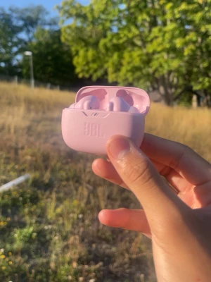 Rosa JBL trådlösa in-ear hörlurar - Säljer ett par snygga rosa trådlösa in-ear hörlurar från JBL med matchande laddningsetui. Hörlurarna har en stilren och kompakt design i plast, perfekt för dig som vill ha bra ljud och smidig användning på språng.