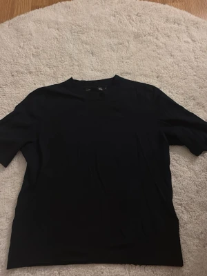 Stickad tröja - En stilren svart t-shirt med rund hals och korta ärmar. Säljer för att den inte används längre 