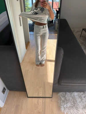 Ljusbeige manchesterbyxor bootcut - Säljer ett par ljusbeige manchesterbyxor med bootcut passform och snygga detaljer som dubbla knappar i midjan. Byxorna har klassiska fickor fram och bak samt diskreta ränder i tyget för en trendig look.
