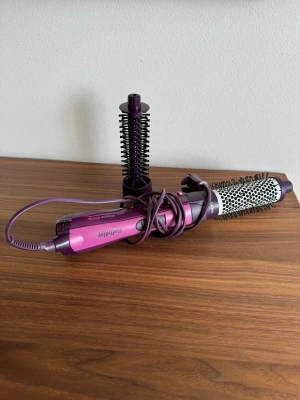 BaByliss Airstyle 800W Värmeborste - Den är designad för att styla och forma håret och har en effekt på 800W. Den kommer med två utbytbara borsthuvuden i olika storlekar för varierande stylingalternativ.