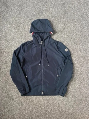  Moncler Vindjacka – Marinblå -  Moncler Vindjacka – Marinblå  Säljer en stilren Moncler vindjacka i marinblått med huva och klassiskt Moncler-märke på ärmen. Perfekt som vår-/höstjacka och passar till det mesta.  📏Storlekar: M & L Finns några stycken i lager  Skick: Ny/fint skick – se bilder 🎨 Färg: Marinblå 💬 Skicka PM vid intresse eller om du vill ha fler bilder/mått.  🚚 Kan skickas eller hämtas enligt överenskommelse. -                                                 NFC - Scan funkar vid märket ! 