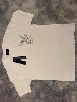 Vit t-shirt från Represent - Snygg vit t-shirt från Represent med tryck av en flygande fågel och texten 'REPRESENT' på bröstet. Klassisk rund halsringning och korta ärmar. Tillverkad i mjukt material som känns skönt mot huden. Perfekt för en clean och stilren look.