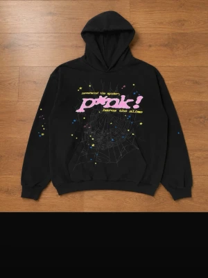 Svart hoodie med tryck från Spåder - Svart hoodie från Spåder med färgglatt tryck framtill i rosa, gult och vitt samt spindelnätsmotiv. Hoodien har huva och ribbade muddar vid ärmar och nederkant. Tillverkad i 100% bomull för en skön och avslappnad känsla.