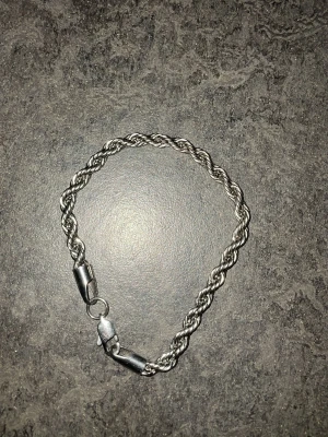 Tunt cordell silverfärgat armband - Snyggt och stilrent cordell armband i silverfärg storlek 19cm/5mm. Armbandet har en enkel karbinhake och passar perfekt för dig som gillar minimalistiska accessoarer. Tillverkat i metall med en glansig finish och smal design.