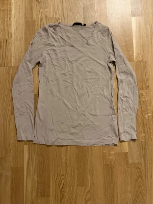 Beige långärmad topp från Indiska - En enkel och stilren beige långärmad topp från Indiska. Tillverkad i mjuk bomull, perfekt att matcha med jeans eller kjol. Klassisk rund halsringning och normal passform.                                                                 Katt finns i hemmet!!