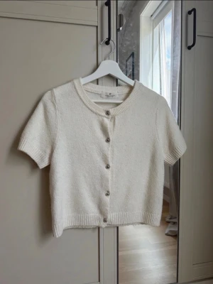 H&M tröja - Stickad T-shirt från h&m med silverfärgade knappar. Tröjan är något nopprig men fortfarande i bra skick. Den är i storlek 158-164 som motsvarar xxs/xs.