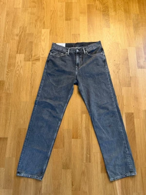 Blå relaxed fit jeans från H&M - Säljer ett par blå jeans från H&M i relaxed fit-modell. Klassisk femficksdesign med raka ben och normal midja. Jeansen är tillverkade i denim och har en avslappnad passform som är både trendig och bekväm.