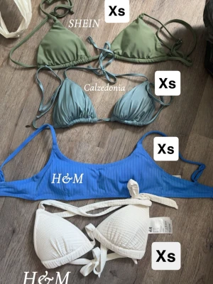 Fyra bikinis i olika färger XS - Fyra snygga bikinis i storlek XS: en olivgrön trekantsbikini från SHEIN, en ljusblå trekantsbikini från Calzedonia, en ribbad blå bikiniöverdel från H&M och en vit trekantsbikini från H&M. Dom två från h&m säljer jag för 40kr styck, SHEIN 30kr och calzedonia 160kr!☺️Aldrig använda!! Har ni några funderingar tveka aldrig på att höra av er!!🥰KÖP INTE INNAN NI SKRIVIT TILL MIG!! ☺️