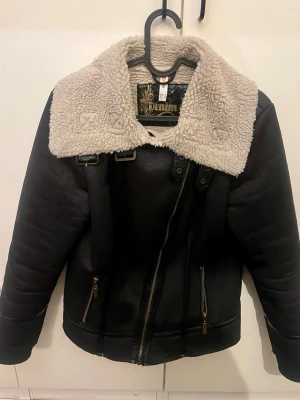 Shearlingjacka - Säljer en snygg shearlingjacka som kan knäppas på olika sätt. Den är köpt second hand och i bra skick, men sliten på loggan på insidan- sista bilden. Skriv vid frågor💞