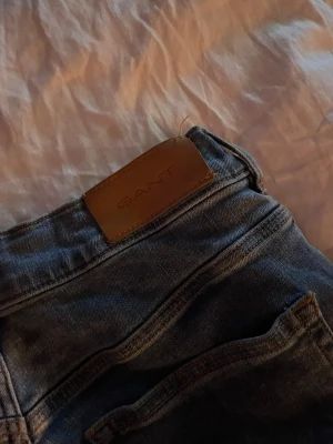 Blå raka jeans från Gant - Säljer ett par klassiska blå jeans från Gant med raka ben och låg midja. Jeansen är knappt använda. Jeansen har fem fickor och en snygg läderpatch med Gant-loggan bak i midjan. Perfekta till vardagsstilen och passar till det mesta. Materialet är denim i bomull. Priset kan diskuteras!