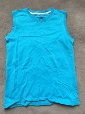 Turkos ärmlös linnetopp - Snygg turkos ärmlös linnetopp i mjuk bomull. Enkel och clean design med rund halsringning, perfekt för varma dagar eller som layering-piece. Passar dig som gillar en avslappnad och fräsch stil.