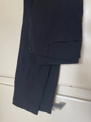 Rosner 42/28 Svarta dam byxor med hög midja - Snygga svarta Rosner Alisa 1 byxor med hög midja och bred linning. Tillverkade i stretchigt material som sitter skönt och formar sig efter kroppen. Perfekta till både oversized tröjor och crop tops. Snygga sömdetaljer längs benen för extra stil. 28 inch i benen Damstorlek 42 