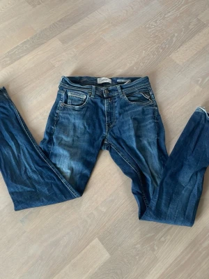 Blå jeans med slitningar - Säljer ett par blå jeans med snygga slitningar och klassisk femficksmodell. Jeansen har normal midja och raka ben. Perfekta till en avslappnad och trendig look.