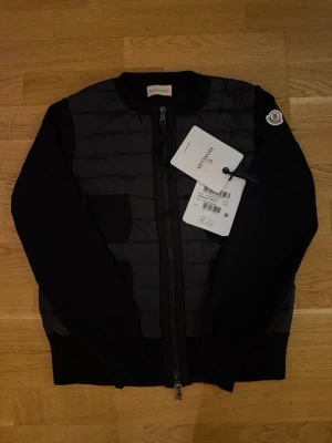 Svart cardiganjacka från Moncler - Svart cardiganjacka från moncler perfekt för dig som vill ha den lilla extra toutchen på en stilren outfit! Har över 10stycken i lagret bara att höra av sig vid köp av 2 eller fler