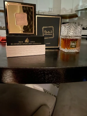 Lattafa Khamrah Eau de Parfum 100ml - Lattafa Khamrah Eau de Parfum i en lyxig, fyrkantig glasflaska med gulddetaljer och elegant mönster. Doften kommer i en snygg svart och guld kartong, vilket ger en exklusiv känsla. Flaskan har ca 95% vätska kvar. 
