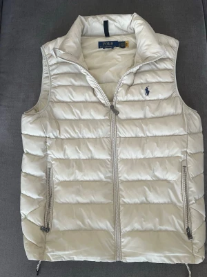 Vit dunväst från Polo Ralph Lauren - En fet Ralph Lauren väst i mycket bra skick. Storlek: S-M. Eftersökt färg som passar perfekt till alla outfits. Priset är alltid diskuterbart!
