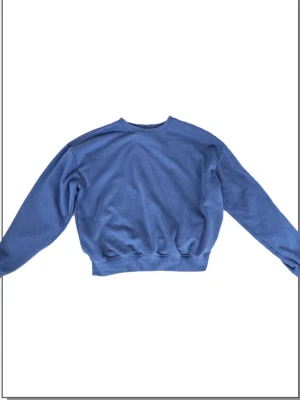 Blå sweatshirt från lager 157 - En enkel och stilren blå sweatshirt från 157 i storlek XS. Tröjan har rund halsringning, ribbade muddar vid ärmslut och midja samt mjukt fleecematerial på insidan. Perfekt för en avslappnad och bekväm look.