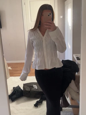 Vit blus från gina tricot - Säljer en vit blus med v-ringad hals. Blusen har långa ärmar och en lätt utsvängd nederkant som ger en feminin siluett. Perfekt att styla med både jeans och kjol för en trendig look. Säljer för den kommer inte till andvändning, prislappen är kvar.