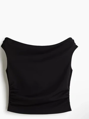 Svart axelbandslös topp - Snygg svart axelbandslös topp med bred urringning och lätt rynkade detaljer i sidorna. Tillverkad i mjukt och stretchigt material som sitter tight mot kroppen. Perfekt att styla med höga jeans eller kjol.