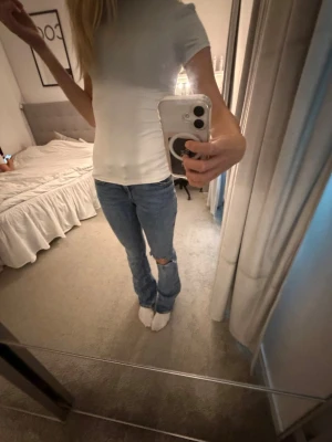 Blå bootcut jeans med hål på knät - Säljer ett par ljusblå bootcut jeans med ett snyggt hål på ena knät. Jeansen har klassisk femficksdesign och normal midja. 