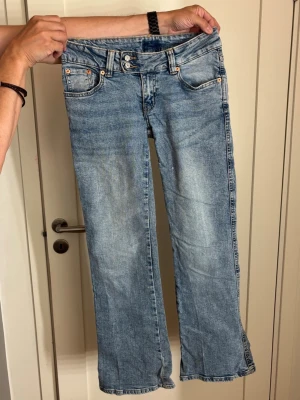 Ljusblå bootcut jeans med brodyr - Säljer ett par ljusblå bootcut jeans med snygg dekorativ brodyr på bakfickorna. 