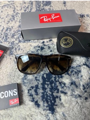Ray-Ban boyfriend solglasögon brun - Säljer ett par klassiska Ray-Ban boyfriend solglasögon i brunmelerad plast med mörka glas. Snygg och tidlös design med Ray-Ban-logga på sidan. Perfekta för soliga dagar och ger en cool vibe till din outfit.
