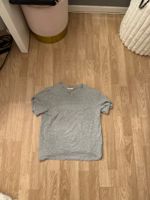 Grå basic t-shirt i bomull - En enkel grå t-shirt med rund hals och korta ärmar. Tillverkad i mjuk bomull och har en klassisk passform som funkar till allt. Perfekt basplagg för garderoben.