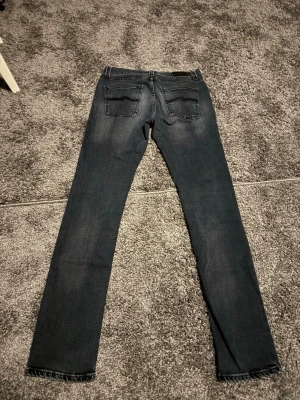 Nudie Lean Dean - Snygga gråa jeans med raka ben och diskreta slitningar framtill. Klassisk femficksmodell med knapp- och dragkedjegylf. Jeansen har en tvättad look och är tillverkade i denim med lätt stretch för skön passform. Pris kan diskuteras! L34 W32