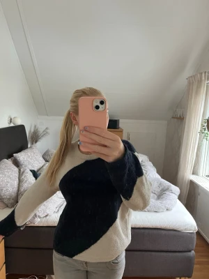 Stickad tröja med svart och vit design - Säljer en snygg stickad tröja med breda diagonala block i svart och vitt. Tröjan har rund halsringning och långa ärmar. Perfekt för dig som gillar en enkel men ändå cool look.