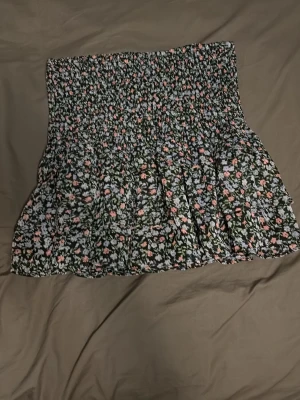 Blommig kortkjol  -  kortkjol från Gina Tricot med blommigt mönster i vitt, rosa och grönt. Storlek S. Använd minst 3 gånger.