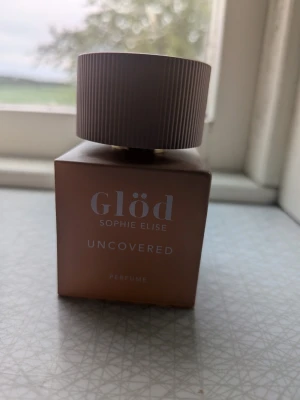Glöd Uncovered parfym - Glöd Uncovered parfym från Sophie Elise i en stilren, fyrkantig flaska med matt beige färg och ett stort räfflat lock. Flaskan har en modern och minimalistisk design som känns lyxig och trendig. Perfekt för dig som vill ha en snygg parfymflaska på hyllan. Minst 90% kvar då den endast är testad
