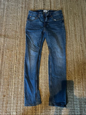 Blå slim fit jeans från 157 - Snygga blå slim fit jeans från 157 med klassisk femficksdesign och dragkedjegylf. Jeansen har en smal passform och är tillverkade i ett mjukt denimtyg som ger en bekväm känsla. Perfekta för dig som gillar en stilren och enkel look.❗️w30 L32❗️
