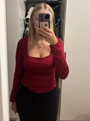 Röd långärmad topp  - Snygg röd långärmad topp med fyrkantig ringning och rynkade detaljer på ärmarna. Tillverkad i ett mjukt och stretchigt material som sitter bekvämt och framhäver figuren. Perfekt för dig som vill ha en enkel men ändå trendig look.