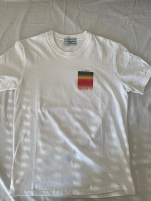 Vit Casa Blanca t-shirt med tryck - Snygg vit t-shirt från Casa Blanca med färgglatt rektangulärt tryck i grönt, gult och rött på bröstet och ryggen. T-shirten har rund hals och korta ärmar, perfekt för en clean och trendig look.