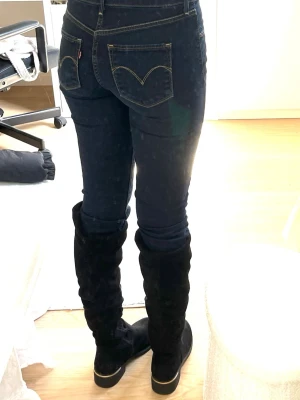 Mörkblå skinny jeans från Levis  - Säljer ett par mörkblå skinny jeans med kontrastsömmar och klassiska fem fickor. Jeansen har en smal passform och medel midja perfekta till boots eller sneakers. Materialet är stretchigt denim som sitter snyggt och bekvämt☺️Det är 26 demi curve 