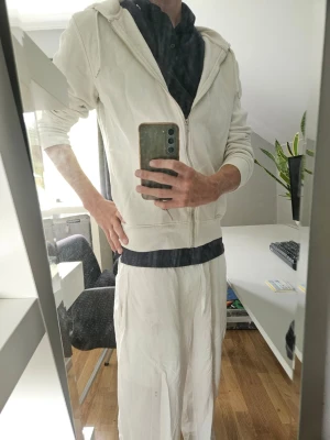 Vit hoodie med dragkedja och huva - Säljer en vit hoodie med dragkedja framtill och huva. Hoodien har långa ärmar och en avslappnad passform, perfekt för en chill och enkel stil. Passar till det mesta och är lätt att matcha med andra plagg.