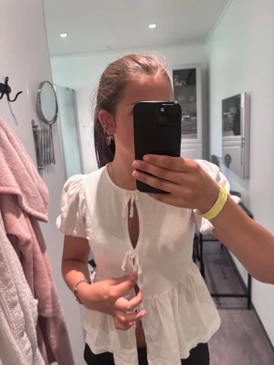 vit topp med puffärm och rosetter.🤍 - säljer denna vita toppen som har puffiga korta ärmar vid axlarna. tröjan har tre rosetter nedtill. håller för eftersom att hålet vid den rosetten syns ganska mycket så man kan behöva ha ett linne under osv. inga skador osv! 🩷