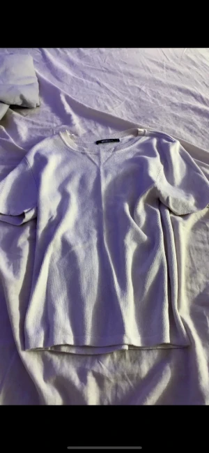 Vit ribbad t-shirt med kort ärm - Säljer en enkel och stilren vit t-shirt med ribbad struktur och rund hals. T-shirten har korta ärmar och en rak passform som funkar till det mesta. Perfekt basplagg för alla tillfällen💕