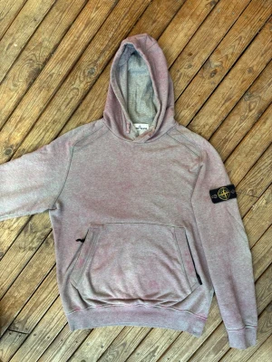 Stone Island rose hoodie - Säljer en Stone Island-huvtröja i färgen “Melange Rose Quartz” från Spring/Summer 2021.  I mycket fint skick.  Storlek M enligt etiketten, men passar bättre som L.  Det syns inte så bra på bilderna, men patchen skimrar också i rosa i verkligheten.  Hör gärna av dig om du vill ha mått! :)
