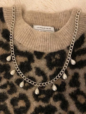 Silverfärgat halsband med pärldroppar - Snyggt halsband i silverfärgad metall med sju droppformade pärlor som hänger längs kedjan. Perfekt accessoar för att lyfta vilken outfit som helst med en trendig och elegant touch. Kedjan har en chunky design och pärlorna ger en cool kontrast.