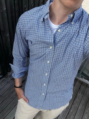 Blårutig skjorta från Ralph Lauren - Snygg blårutig skjorta från Ralph Lauren i slim fit-modell. Skjortan har klassisk krage, knappar framtill och långa ärmar. Perfekt för dig som gillar en stilren och fräsch look. Tillverkad i bomull för en skön känsla.