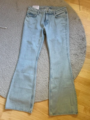 Ljusblå bootcut jeans från Weekday - Säljer ett par ljusblå bootcut jeans från Weekday. Jeansen har klassisk femficksmodell, midwaist och utsvängda ben. Tillverkade i denim med en snygg tvätt som ger en fräsch och trendig look. Perfekta för dig som gillar retrovibbar och vill sticka ut. Ordinarie pris 699kr. 