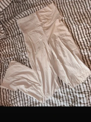 Vita vida mjukisbyxor Gina Tricot - Säljer ett par vita mjukisbyxor från Gina Tricot med fold over midja och vida ben. Byxorna är gjorda i mjukt och stretchigt material, perfekta för chill dagar. Snygg och enkel design som passar till allt.