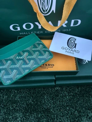 Grön plånbok  - Snygg grön korthållare  med det klassiska mönstret i vitt och grått. Tillverkad i canvas och läder, perfekt för kort och ID. Kommer med originalförpackning och dustbag.