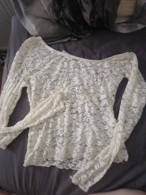 Vit spetsblus från ASOS DESIGN - Säljer en superfin vit spetsblus från ASOS DESIGN. Blusen har lång ärm, är genombruten med blommigt spetsmönster och har en lätt loose passform. Perfekt att styla med jeans eller kjol för en trendig look.