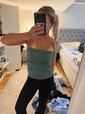 Grön axelbandslös tubtopp - Snygg grön tubtopp med axelbandslös design. Toppen har en enkel och stilren look med tight passform och är perfekt att matcha med både jeans och kjol. Materialet känns mjukt och stretchigt för en bekväm känsla. Vet ej storlek men passar xs/s