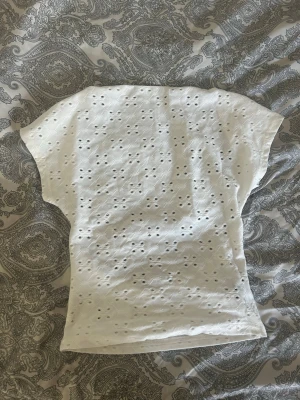 Vit topp med broderade hål och öppen rygg - Helt oanvänd!! Kontakta om frågor!