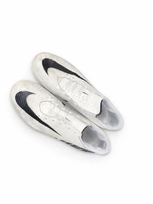 Vita Nike fotbollsskor med svart swoosh - Säljer ett par vita Nike fotbollsskor med stor svart swoosh på sidan. Skorna har låg profil, snörning och ventilerande hål på ovandelen. Tillverkade i syntetmaterial för bra grepp och känsla på planen. Perfekta för dig som vill sticka ut på matchen.