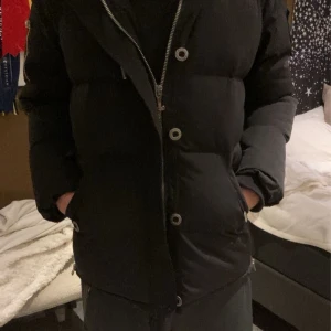 Moose Knuckles jacka  - Säljer en svart dunjacka från Moose Knuckles i nyskick. Jackan har en fluffig vit pälsdetalj på huvan och snygga dragkedjor och knappar framtill. Perfekt för kalla vinterdagar! 🖤 nypris 14100kr